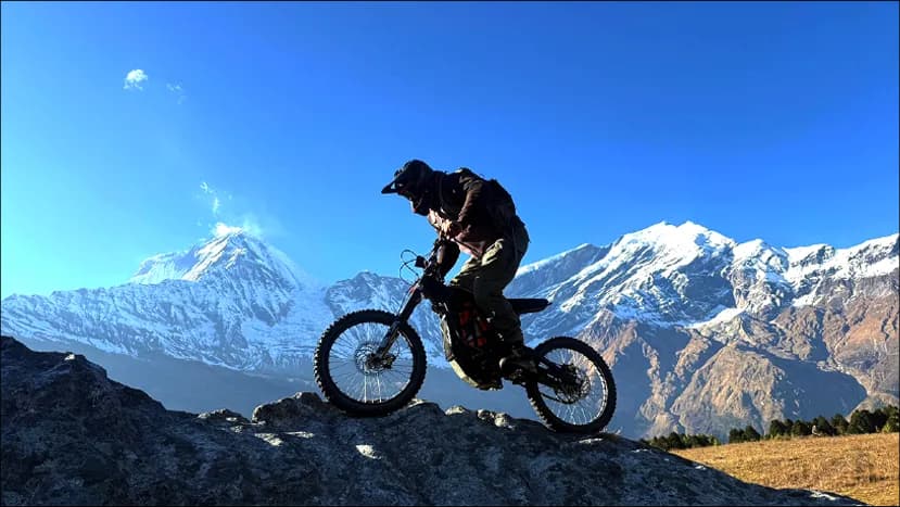 Rider lifting the front wheel on a rocky ridge above the Annapurna range