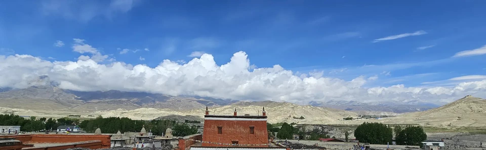 Walled Mustang settlement of red and white houses below the Himalayan ridgeline