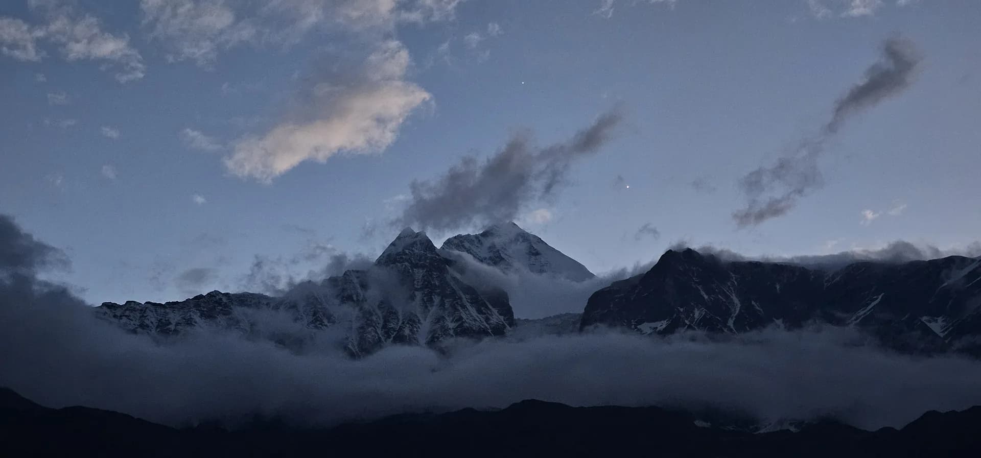 Snow-capped Himalayan peaks rising above a sea of cloud at dusk