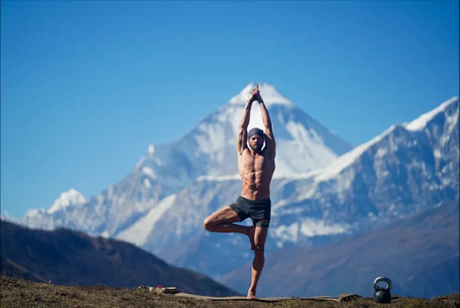 Man holding a standing yoga pose before the Dhaulagiri massif