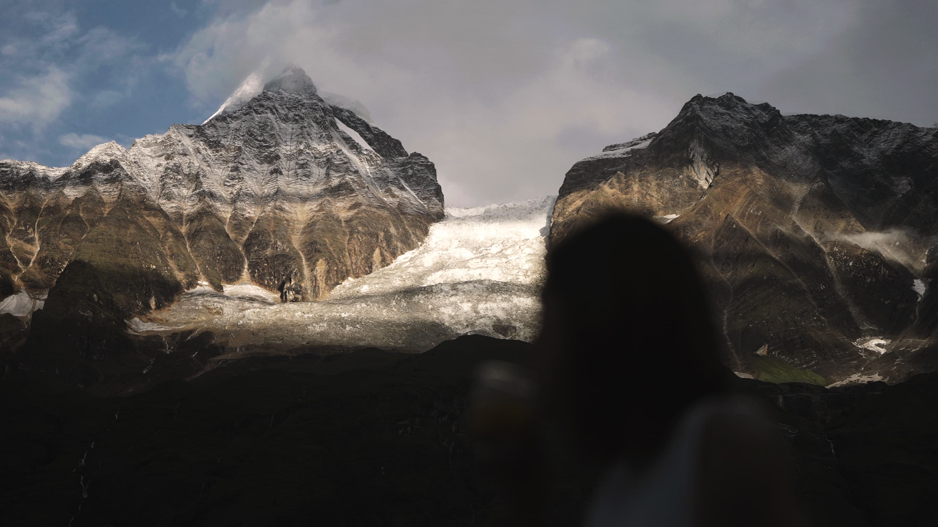 Glacier and snow peaks seen from the camp over a guest's shoulder